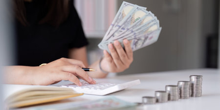 Women is keeping a record of his income and expense, he plans his finance by using his monthly...