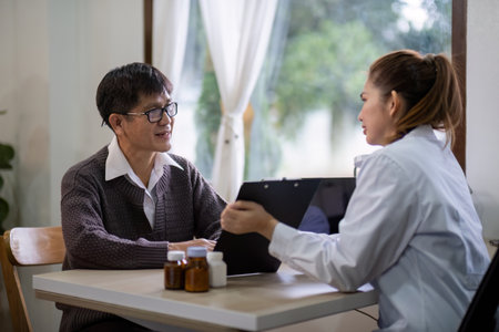 Senior east asian man discussing health with female doctor indoorsの写真素材