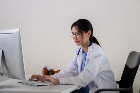 Asian Female Doctor Working on Computer in Medical Officeの写真素材