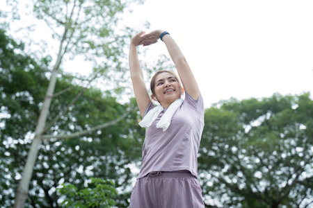Asian woman stretching after a run in a park