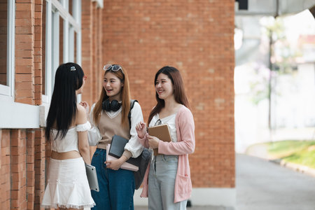 Students socializing outside a school building. Group of young friends talking and laughing on campus. Concept of education, friendship, and student lifeの写真素材