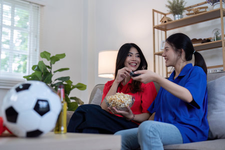 Asian lesbian couple watching Euro football match at home. Concept of cheer and footballの写真素材