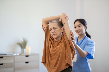 Asian caregiver assisting elderly woman with arm stretch at home. Concept of elderly care and...