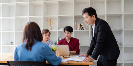 Diverse Business Team Engaged in Analysis and Discuss in Modern Office Setting with Open Shelving Backgroundの写真素材