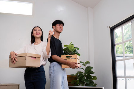 Happy Couple Moving into New House with Boxes and Plants, Excited About New Home, Bright Modern...