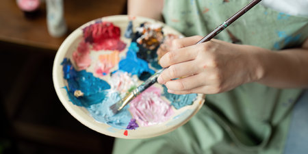 Artist Painting in Workshop with Palette and Brush, Creating Colorful Artwork in Studio, Close Up of Hand and Paints, Creative Process, Artistic Expression, Professional Art Studio Environmentの写真素材