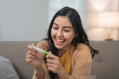Joyful Woman Celebrating Positive Pregnancy Test Result at Home, Expressing Happiness and Excitement