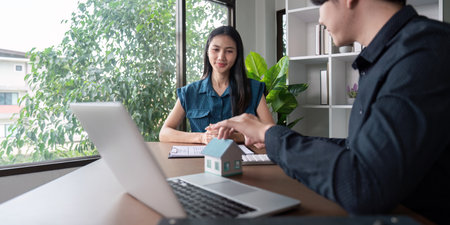 Real Estate Agent and Client Discussing Home Purchase Contract in Modern Office Settingの写真素材