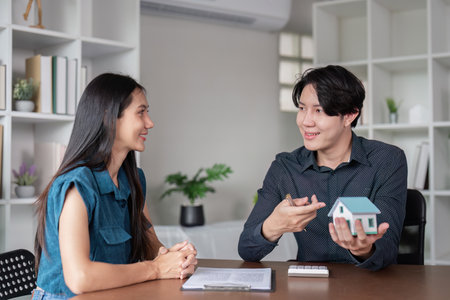 Real Estate Agent Discussing Property Sale Contract with Client in Modern Office Settingの写真素材