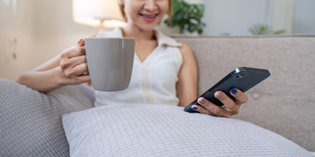 Woman Relax on Couch Enjoying Coffee and Browsing Social Media on Smartphone in Cozy Home Setting