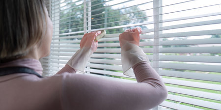 Housekeeper Cleaning Window Blinds with Gloves in a Modern Home, Focusing on Cleanliness