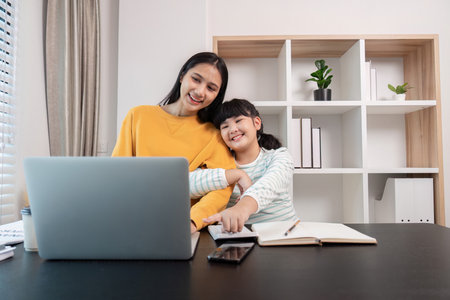 Mother and Child Working from Home Together on Laptop in Modern Home Office Settingの写真素材