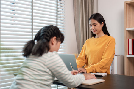 Mother and Child Working from Home Together in a Modern Home Office Setting with Natural Lightの写真素材