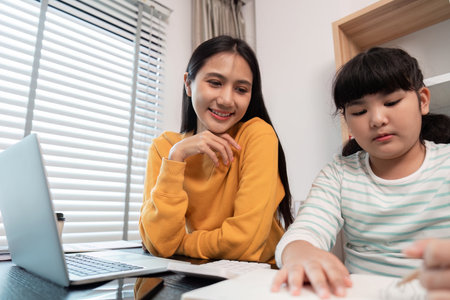Mother and Child Working from Home Together on a Laptop and Homework in a Modern Home Office Settingの写真素材