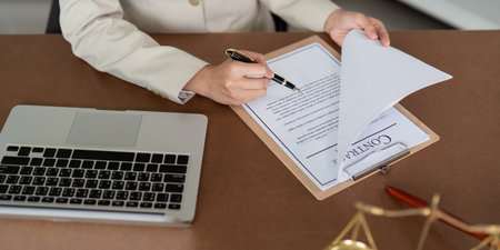 Professional Lawyer Reviewing Contract at Desk with Laptop and Legal Documents in Office Setting