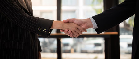 Professional Business Handshake Between Two Individuals in Formal Attire in a Modern Office Setting