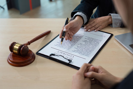 Professional Lawyer Discussing Contract Details with Client in Modern Office Settingの写真素材