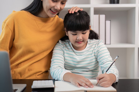 Mother and Daughter Bonding at Home: Smiling Mom Helping Young Girl with Homework in Cozy Modern Living Roomの写真素材