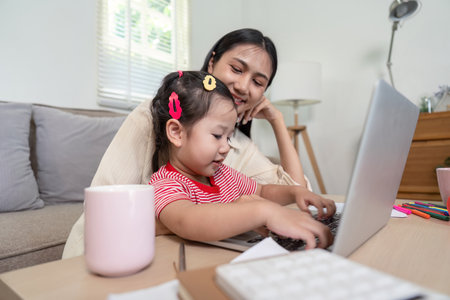 Mother and Daughter Bonding Over Laptop, Teaching and Learning at Homeの写真素材
