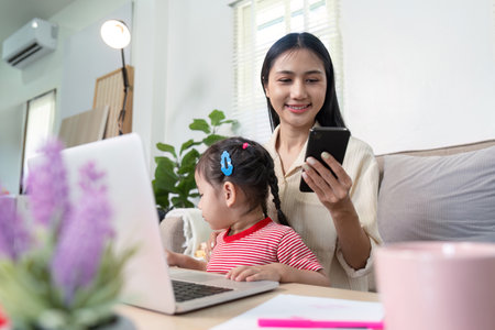 Mother Working from Home with Daughter, Balancing Work and Family Life in a Modern Home Office Settingの写真素材