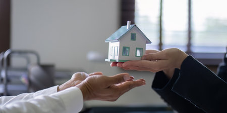 Hands Exchanging House Model in Real Estate Negotiationの写真素材