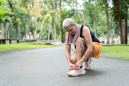 Elderly woman tying shoelaces before jogging in park