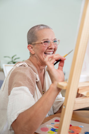 Enthusiastic Senior Artist Smiling While Creating Canvas Artworkの写真素材