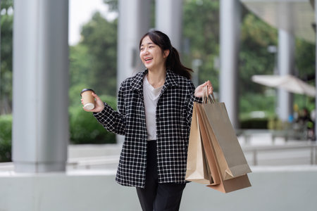 Excited Shopper Balances Coffee Cup with Black Friday Shopping Bagsの写真素材