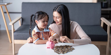 Mother Teaching Daughter About Savings with Piggy Bankの写真素材