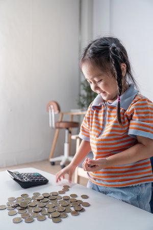 Young Girl Counting Coins With Calculator for Early Financial Educationの写真素材