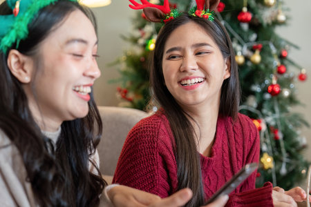 Laughing Lesbian Couple Amidst Festive Decor Sharing Lighthearted Christmas Momentsの写真素材