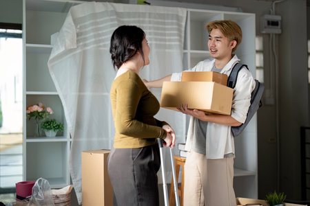 Young Asian couple chatting while unpacking in new home