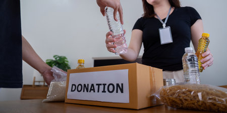 Volunteers Packing Items into Donation Box for Charity
