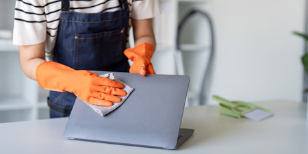 Cleaner polishing laptop with care in a professional setting