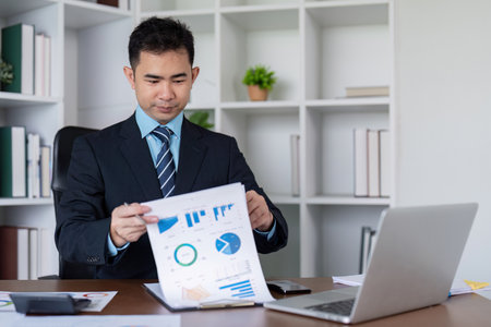 Business Executive Reviewing Financial Graphs at Deskの写真素材