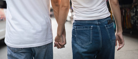 Casual Asian couple holding hands, enjoying a romantic stroll through a market.