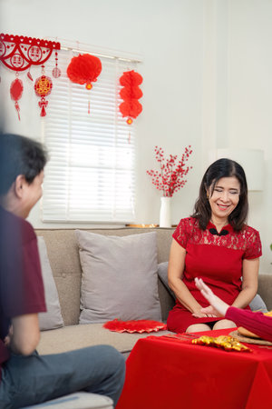 Elderly couple celebrates chinese new year at home living room family gathering joyful environment close-up view traditionsの写真素材