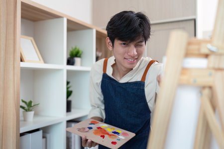 Creative young artist painting in modern studio indoor setting inspirational atmosphere close up perspectiveの写真素材