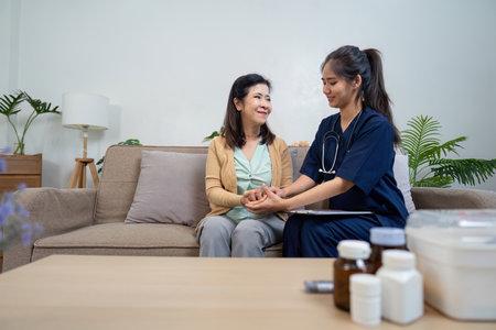 Caregiver checks symptoms of elderly patient with doctor and nurse in home environmentの写真素材