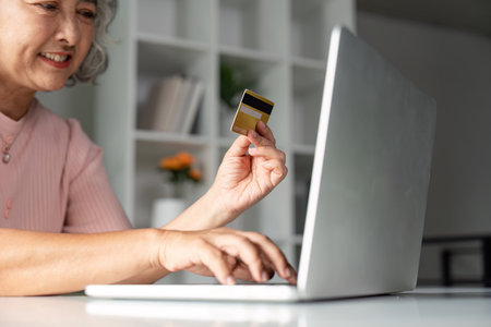 Elderly senior shopping online with credit card in home office environment for convenienceの写真素材