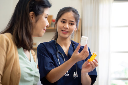 Empathetic caregiver explaining medication use to elderly patient in a home settingの写真素材