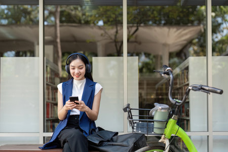 Friendly businesswoman enjoying music on her phone beside an eco-friendly bikeの写真素材