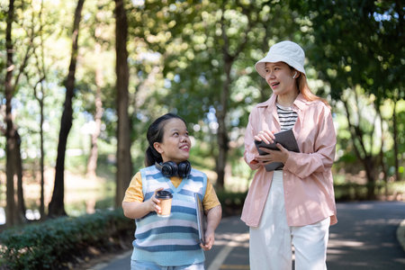 Diverse friends enjoying a cheerful walk in the park, sharing ideas and drinks with tablets in hand