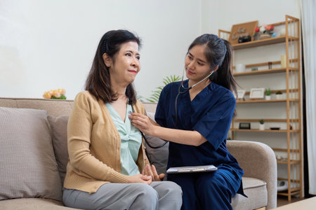 Caregiver using stethoscope to check heartbeat of elderly patient in a cozy home setting