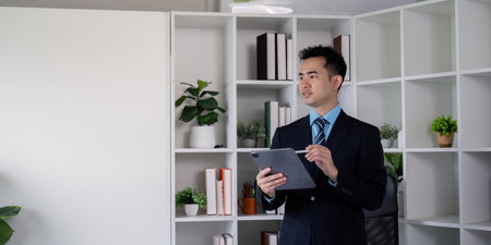 Businessman presenting financial reports using a tablet in a modern office settingの写真素材