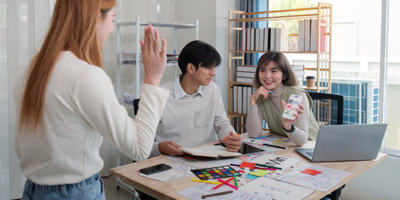 Creative UX UI team collaborating on design project in a modern office, showcasing diverse professionalsの写真素材