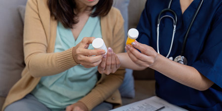 Caregiver discussing medication with elderly patient, addressing disease symptoms and health...