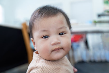 Adorable baby with curious gaze in a cozy indoor setting, showcasing innocence and charm