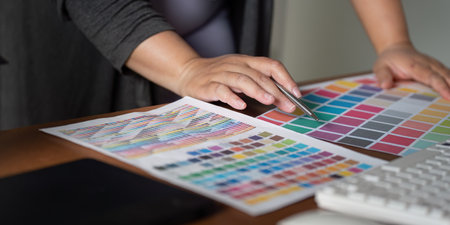 Focused graphic designer selecting color swatches and working on design concepts in a modern office...