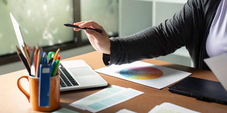 Graphic designer using a stylus at her desk while exploring color palettes and digital tools